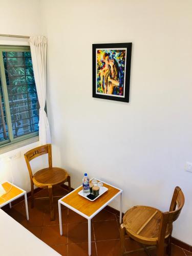 a room with two chairs and a table and a picture on the wall at The Canopy Guest House in Auroville