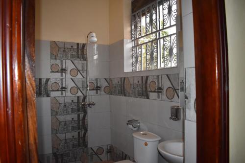 a bathroom with a toilet and a window at Trinity Resort Hotel & Spa in Kampala