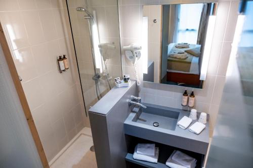 a bathroom with a sink and a shower with a mirror at Mercure Amiens Cathédrale in Amiens