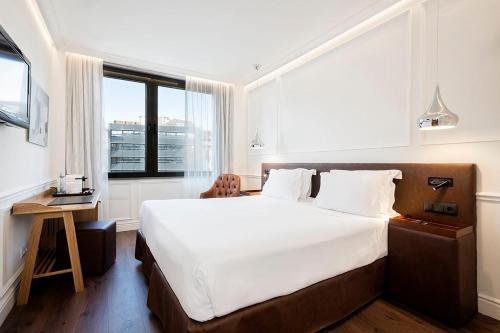 a bedroom with a large white bed and a window at H10 Itaca in Barcelona