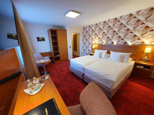 a hotel room with a large bed and a desk at Ringhotel Paulsen in Zeven