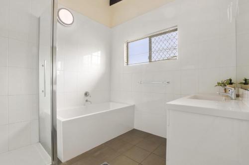 La salle de bains blanche est pourvue d'une baignoire et d'un lavabo. dans l'établissement William St 1 70 Moffat Beach, à Caloundra