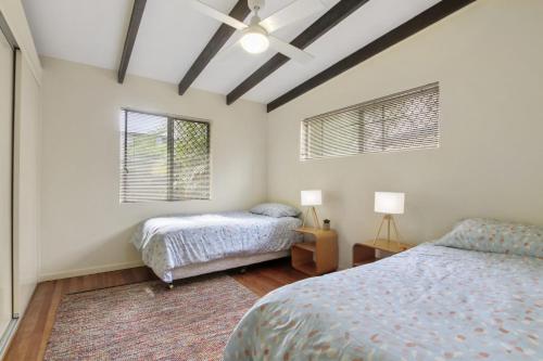 a bedroom with two beds and two windows at William St 1 70 Moffat Beach in Caloundra
