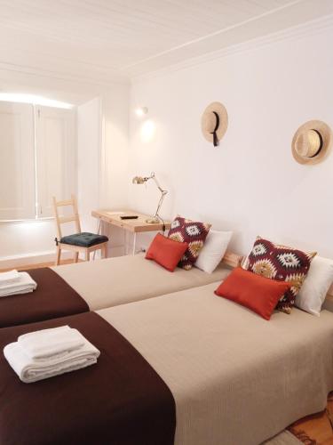 two beds in a room with a table and a chair at Casa da Umbria in Odemira