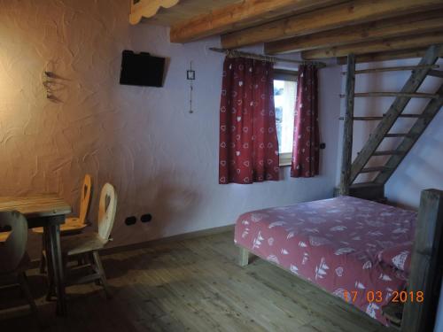 a bedroom with a bunk bed and a table and a window at La Ferme du Grand Paradis in Cogne