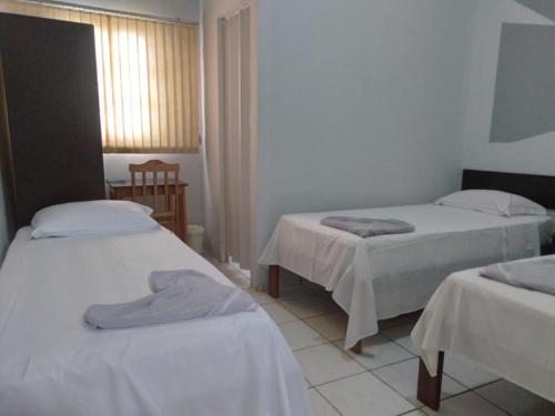 een kamer met 2 bedden met witte lakens en een raam bij Fabiel Palace Hotel in Cuiabá