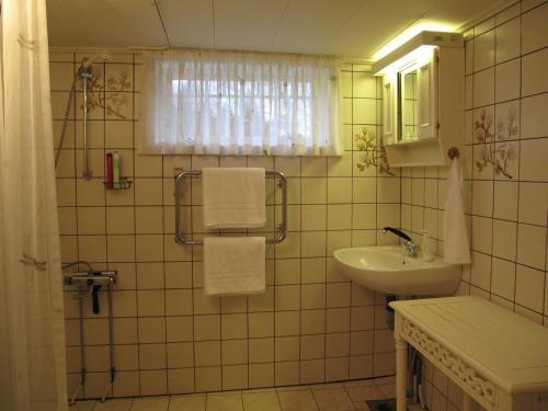 a white tiled bathroom with a sink and a mirror at Villa Luna Breakfast Hotel in Killeberg