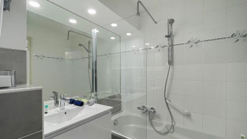 a white bathroom with a shower and a sink at Louison Appart & Suite in Quiberon
