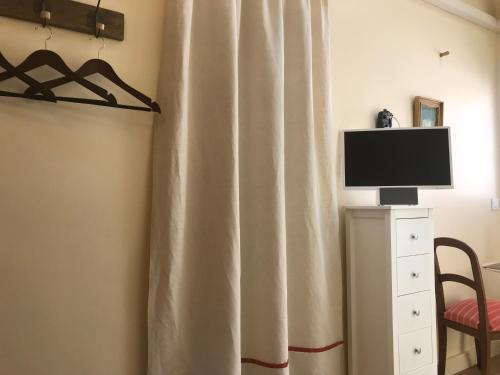 a television sitting on a stand next to a curtain at Simone's Tiny House in Montpellier