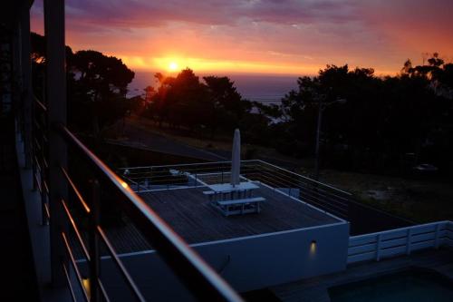 a sunset on a building with a bench on the roof at Camps Bay Loft with Stunning Mountain and Ocean Views in Cape Town