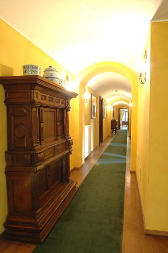 a hallway with a large wooden cabinet and a green carpet at Hotel Torre di San Martino in Gazzola Di Rivalta