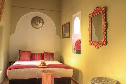 a bedroom with a bed with red pillows and a mirror at Riad Dar Habiba by Garden Wonders in Marrakech