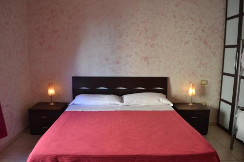 a bedroom with a red bed with two lamps on tables at Sa Marina in La Caletta
