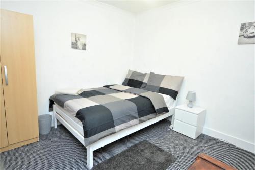 a bedroom with a bed with black and white pillows at Lovely 3 Bedroom House near Barking Station in Barking