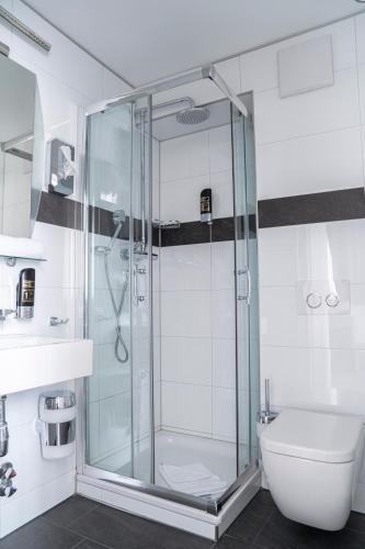 a glass shower in a bathroom with a toilet at Alpha & Omega Hotel in Stuttgart