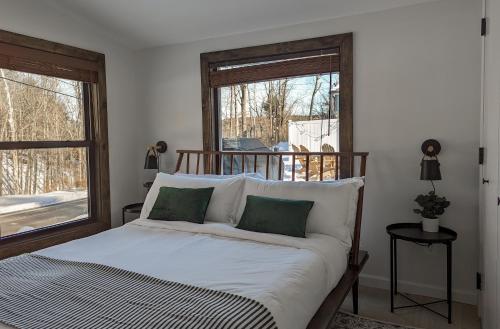 een bed met witte lakens en groene kussens in een slaapkamer bij Acorn Lodge - Luxury Cabin, Catskills, Windham Mountain, Hunter Mountain in Cairo