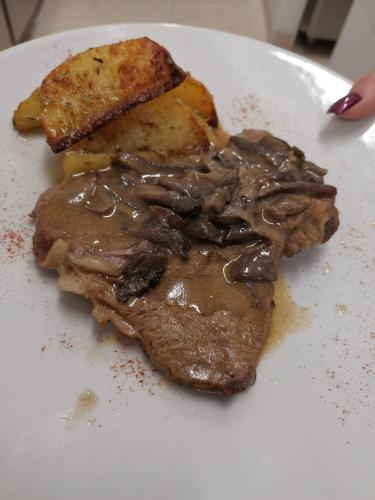 a white plate with a piece of meat and a sandwich at Hotel Parco delle Querce in Crispiano