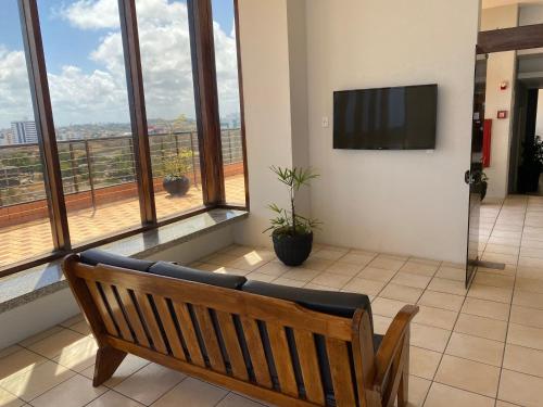 a wooden bench in a room with a large window at Flat beira mar, Olinda 4 Rodas 315 in Olinda