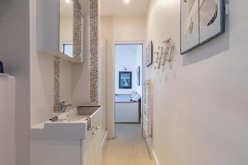 een witte badkamer met een wastafel en een koelkast bij Le Celtic in Saint-Cast-le-Guildo