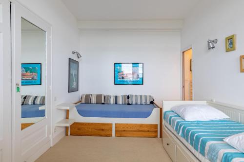 a white bedroom with a bed and a mirror at Le Celtic in Saint-Cast-le-Guildo