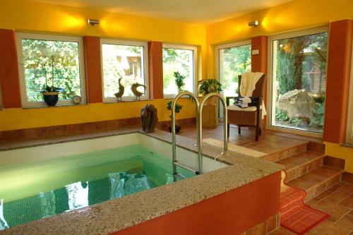 a bathroom with a large tub with windows at Hotel Vinum in Niederwurschnitz