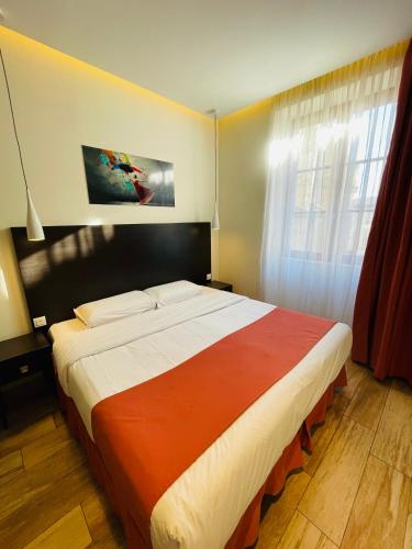 a bedroom with a large bed with an orange and white blanket at Central Hotel in Nîmes
