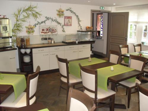 a restaurant with tables and chairs and a kitchen at Hôtel du Haut Koenigsbourg- entre vignes et château in Thannenkirch