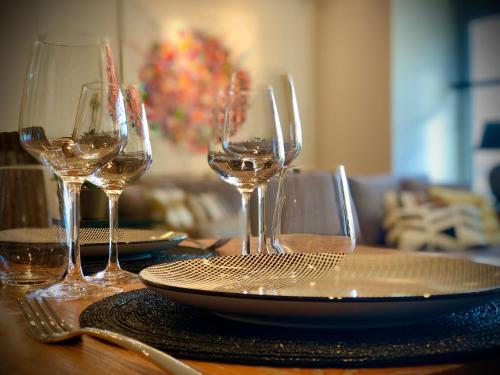 a table with three wine glasses and a plate on it at Appartement Sunny home Deluxe in Knokke-Heist