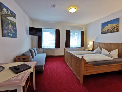 Habitación de hotel con cama y sofá en Hotel Garni Post, en Grainau