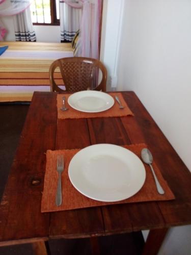 a wooden table with two white plates on it at Villa Maleena in Hikkaduwa