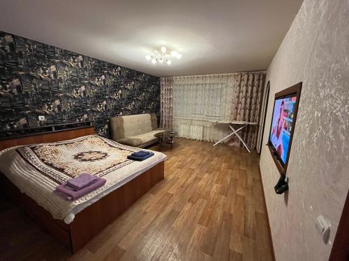 a bedroom with a bed and a tv in it at Apartment Zavenyagina 2 in Noril'sk