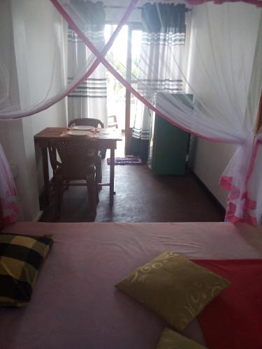 a bedroom with a bed and a desk and a table at Villa Maleena in Hikkaduwa