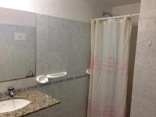 y baño con cortina de ducha y lavamanos. en Hotel Mediterraneo en Villa Carlos Paz