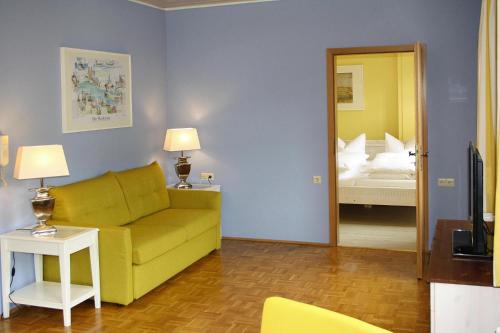 ein Wohnzimmer mit einem gelben Sofa und einem Bett in der Unterkunft Apartment Bears, Meersburg in Meersburg