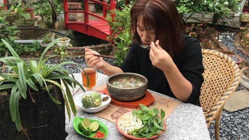 Maison Teahouse homestay في ها زانغ: امرأة تجلس على طاولة مع وعاء من الطعام