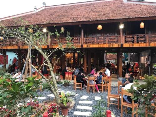 eine Gruppe von Menschen, die an Tischen vor einem Gebäude sitzen in der Unterkunft Maison Teahouse homestay in Ha Giang