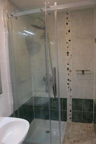 eine Dusche mit Glastür neben einem Waschbecken in der Unterkunft Lou Prat in Meyrueis