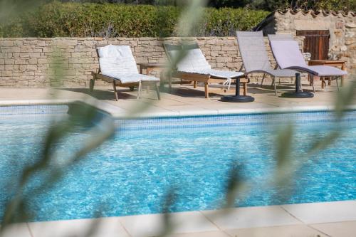 Puyvert的住宿－Maison d'hôtes Bastide St Victor à 2,5 kilomètres de Lourmarin，游泳池旁的一排椅子