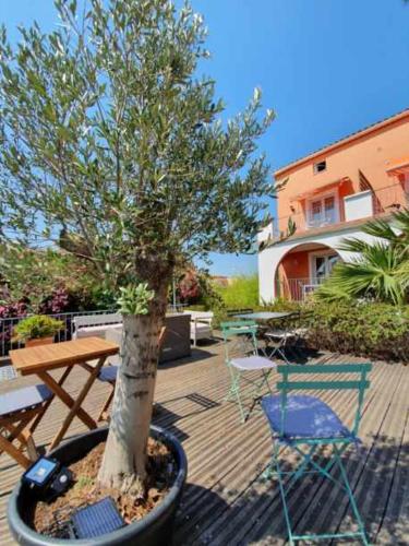 a tree in a pot next to a table and chairs at Hôtel Athéna in Agde