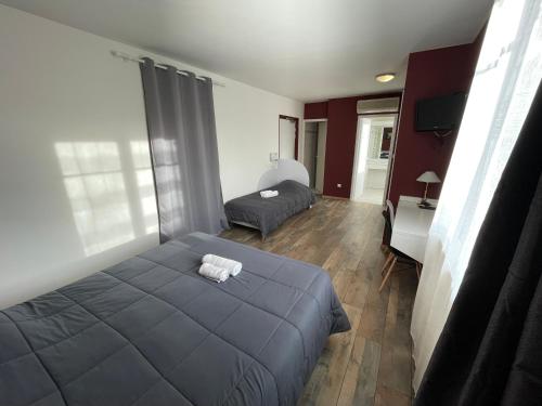 a bedroom with a large bed and a desk at Hotel Les Chênes in Sisteron