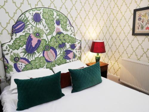 a bedroom with a white bed with a floral headboard at The Fleece in Witney