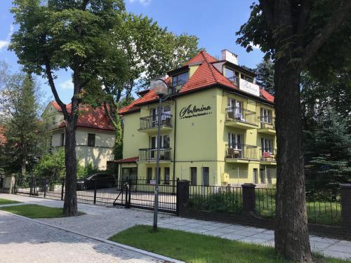 żółty budynek z czerwonym dachem w obiekcie Antonina ***PensjonPrzyKortach*** w Szczawnie Zdroju
