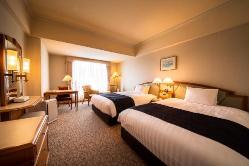 a hotel room with two beds and a desk at Kure Hankyu Hotel in Kure