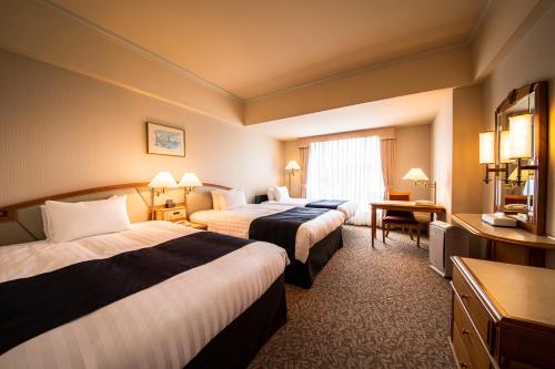 a hotel room with two beds and a television at Kure Hankyu Hotel in Kure