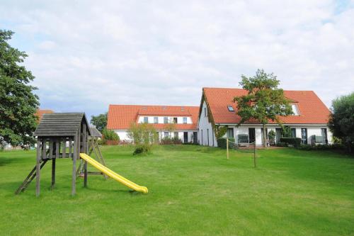 a playground with a slide in a yard with a house at Apartments Post Hiddensee Vitte in Vitte