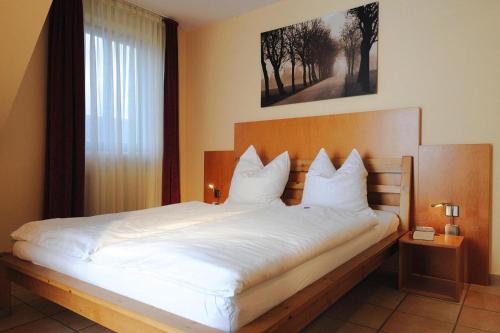 1 dormitorio con 1 cama grande con sábanas blancas y ventana en Apartments Post Hiddensee, Vitte en Vitte