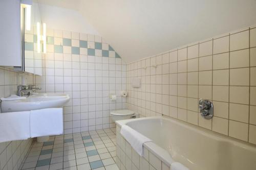 a bathroom with a sink and a tub and a toilet at Apartments Post Hiddensee, Vitte in Vitte
