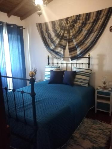 a bedroom with a blue bed with blue curtains at Casa da Avó Rita in São Pedro do Corval