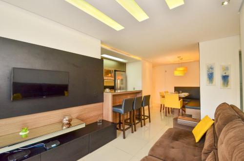 a living room with a couch and a television on a wall at Jurerê para 6 hóspedes a 2 quadras da praia N1705 in Florianópolis