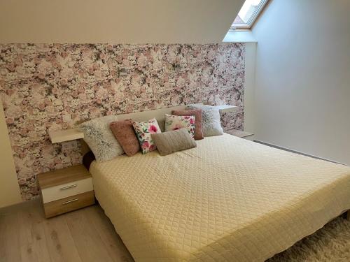 Un dormitorio con una cama con una pared de acento floral en Zen Apartman, en Eger